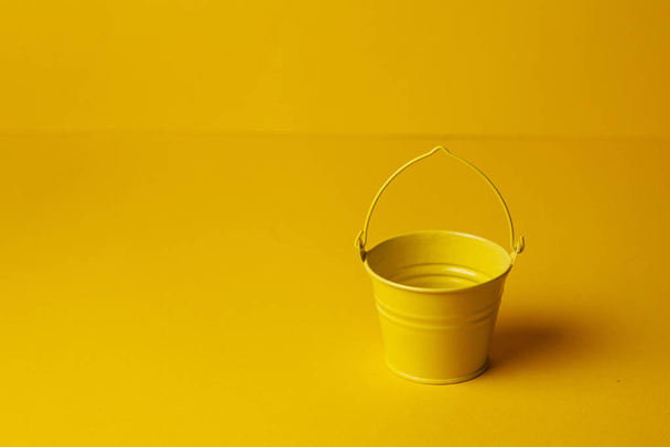 yellow empty small bucket for gardening on a yellow background, summer concept, season of vegetable gardens - Fotoğraf, Görsel