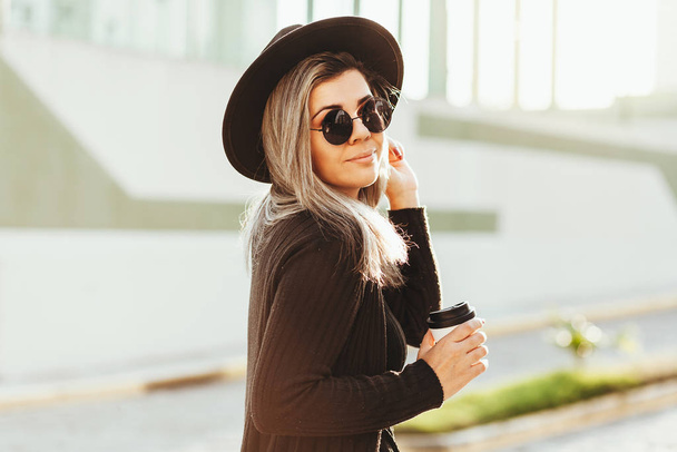 Outdoor portrait of woman wearing fedora hat and sunglasses - Фото, изображение