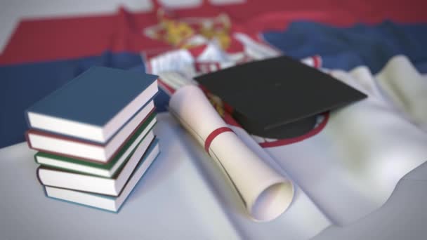 Diploma sapka, könyvek és oklevelek a szerb zászlón. Felsőoktatás Szerbiában kapcsolódó konceptuális 3D animáció - Felvétel, videó