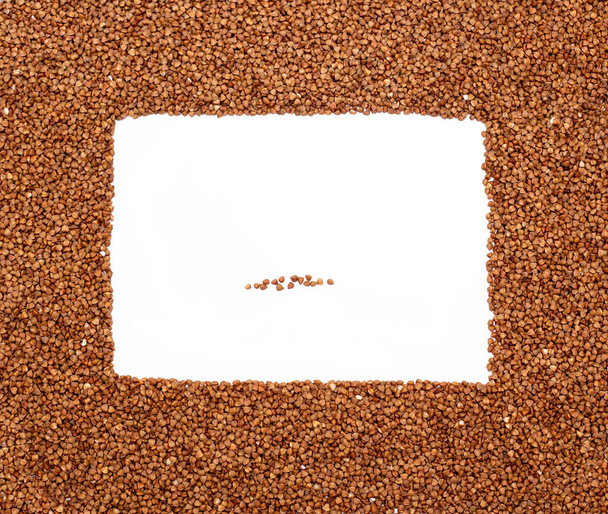 Brown buckwheat groats on white background. Top view, copy space, frame - Foto, immagini
