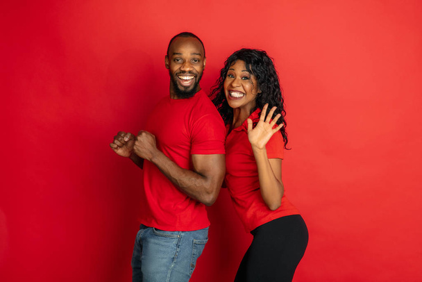 Young emotional african-american man and woman on red background - Valokuva, kuva
