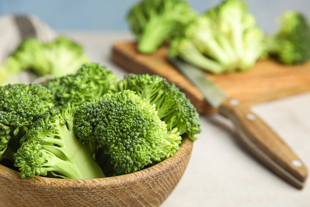 Fresh green broccoli in wooden bowl on light table, closeup - Foto, Bild