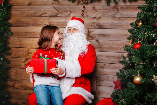 Mikołaj słuchający życzeń małych dziewczynek. Koncepcja świąteczna - Zdjęcie, obraz
