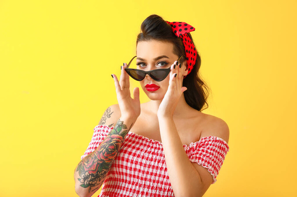 Portrét krásné tetované pin-up žena na barevném pozadí - Fotografie, Obrázek