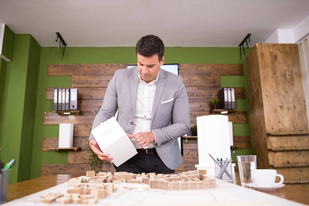 Молодий архітектор тримає модель будівлі в конференц-залі
 - Фото, зображення