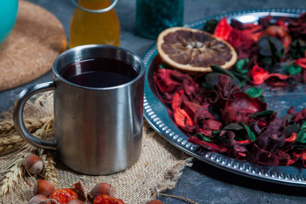 Chá Hibiscus quente vermelho em uma caneca de vidro em uma mesa de madeira entre pétalas de rosa e creme de chá seco com carcade
 - Foto, Imagem