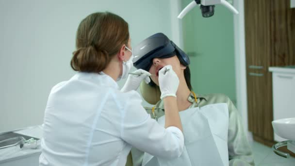 Zahnarzt arbeitet, Mädchen sitzt mit Virtual-Reality-Brille - Filmmaterial, Video