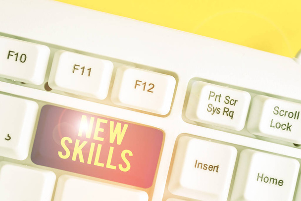 Text sign showing New Skills. Conceptual photo Recently Acquired Learned Abilities Knowledge Competences White pc keyboard with empty note paper above white background key copy space. - 写真・画像