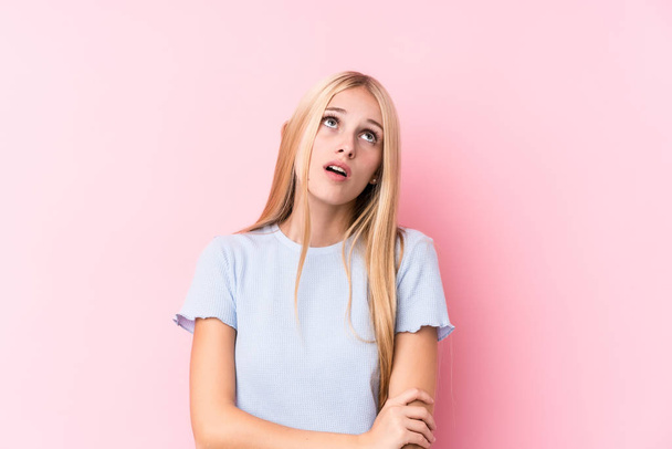 Young blonde woman on pink background tired of a repetitive task. - Photo, Image