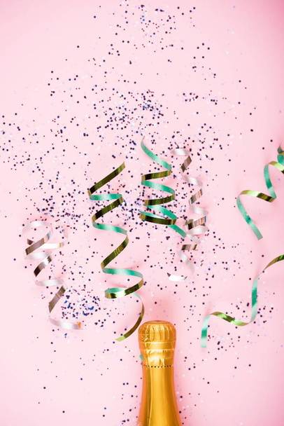 Flache Feierstunde. Champagner-Flasche mit bunten Party-Luftschlangen auf Mint-Hintergrund. - Foto, Bild