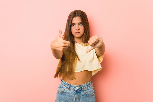 Young slim woman showing thumbs up and thumbs down, difficult choose concept - Photo, Image