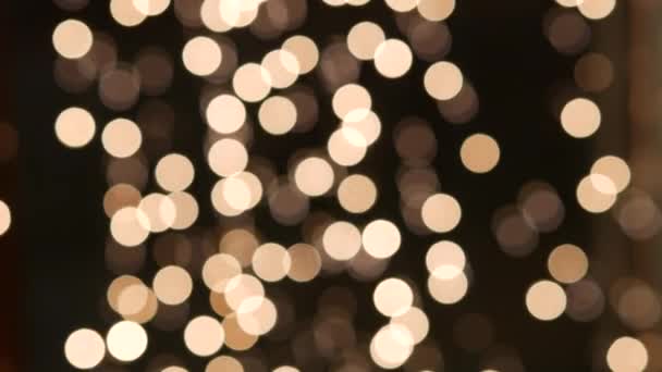 Blurred bokeh holiday lights background. Garland of miniature LED bulbs sway - Footage, Video