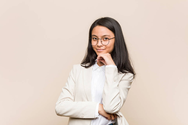 Νεαρή Κινέζα επιχειρηματίας χαμογελώντας ευτυχισμένη και με αυτοπεποίθηση, αγγίζοντας το πηγούνι με το χέρι. - Φωτογραφία, εικόνα