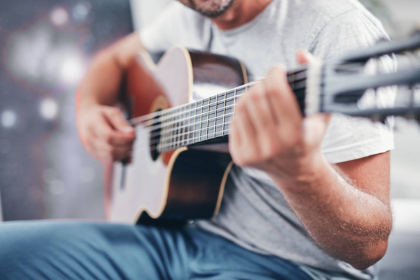 чоловік грає на акустичній гітарі у вітальні
. - Фото, зображення