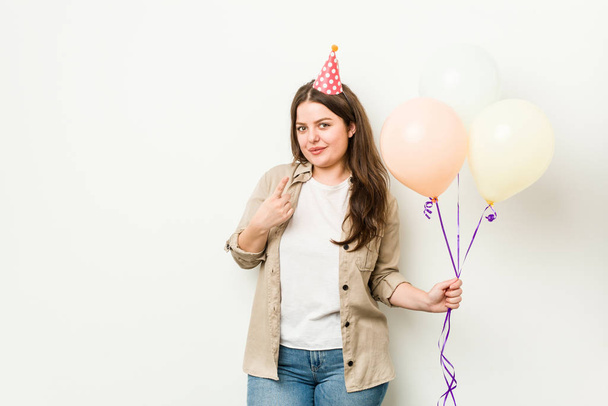 Jovem mais tamanho mulher curvilínea celebrando um aniversário apontando com o dedo para você como se convidando chegar mais perto
. - Foto, Imagem