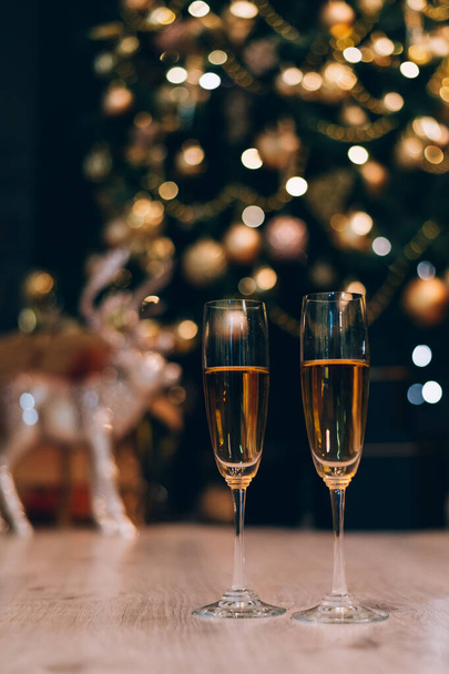 Kaksi lasia samppanjaa seisoo hämärtynyt koristeltu joulukuusi tausta
. - Valokuva, kuva