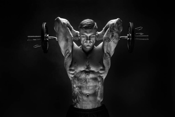 Strong sportsman lifting heavy dumbbell in smoke - Φωτογραφία, εικόνα