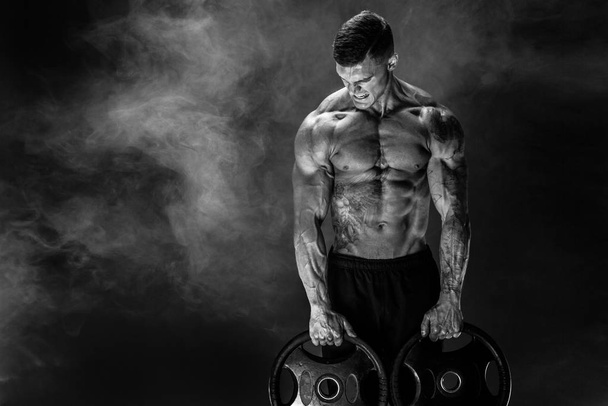 Bodybuilder with dumbbells in his arms - 写真・画像