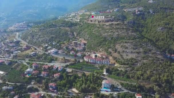 Létání nad slunným městem Alanya v Turecku se nachází u Středozemního moře. Umění. Letecký pohled na horský svah pokrytý domy a stromy. - Záběry, video