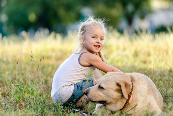 Petite fille joue avec un labrador dans le parc. - Photo, image
