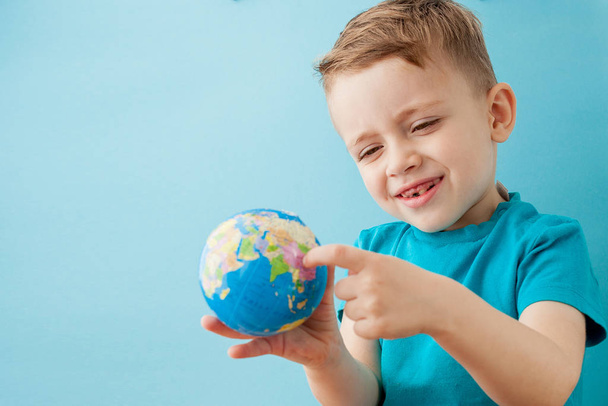 Little boy holding a globe on blue background - Φωτογραφία, εικόνα