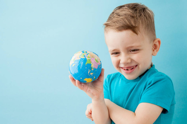 Little boy holding a globe on blue background - Foto, Imagem