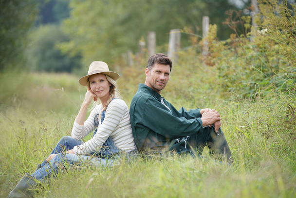 Couple of farmers sitting in field - Фото, изображение