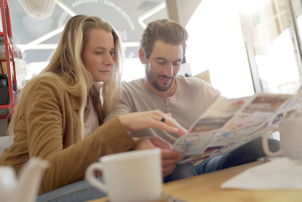 Young couple watching a newspaper in a coffee shop - Foto, Imagem