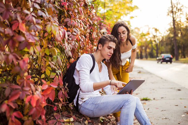 Νεαροί φίλοι περιηγούνται στο διαδίκτυο με ένα ψηφιακό tablet στο stree - Φωτογραφία, εικόνα