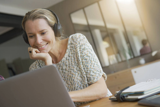 young blonde woman working in an office with headphones - Foto, Bild