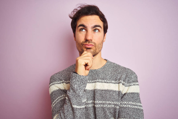 Young handsome man wearing casual striped sweater standing over isolated pink background serious face thinking about question, very confused idea - Φωτογραφία, εικόνα
