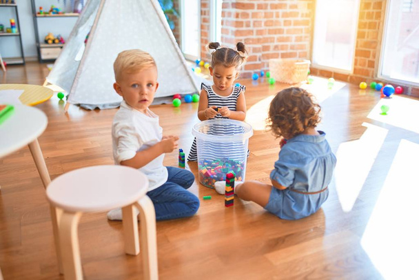 Adorable grupo de niños pequeños jugando alrededor de un montón de juguetes en el jardín de infantes
 - Foto, imagen
