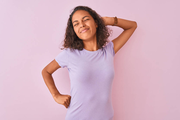 Young brazilian woman wearing t-shirt standing over isolated pink background stretching back, tired and relaxed, sleepy and yawning for early morning - Fotografie, Obrázek