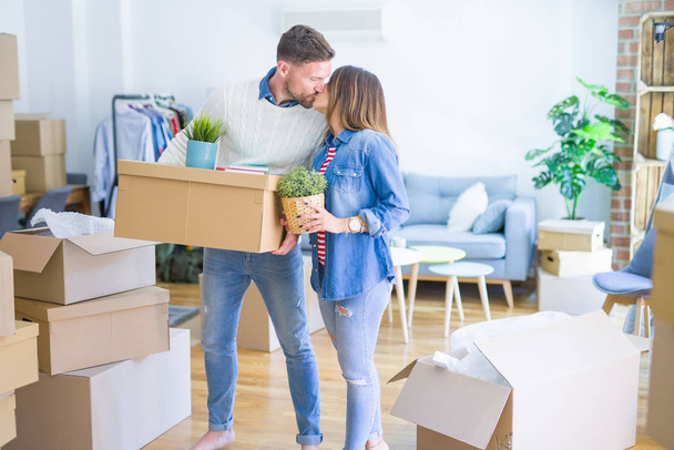 Joven hermosa pareja moviendo cajas de cartón y besándose en un nuevo hogar
 - Foto, Imagen