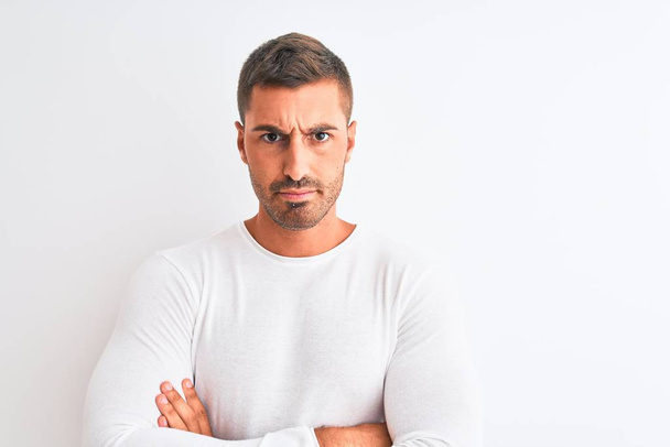 Young handsome man wearing white shirt over isolated background skeptic and nervous, disapproving expression on face with crossed arms. Negative person. - Fotoğraf, Görsel