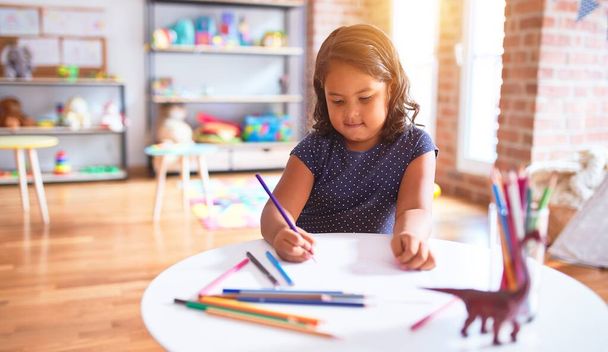 Gyönyörű kisgyermek lány rajz aranyos sorsolás segítségével színes ceruzák óvodában - Fotó, kép