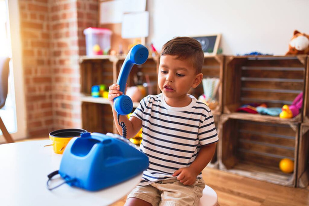 Schönes Kleinkind spielt im Kindergarten mit blauem Telefon - Foto, Bild