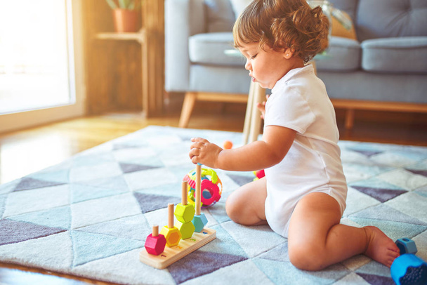 Красива дівчинка-малюк грає з іграшками на килимі
 - Фото, зображення