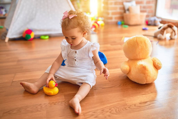 schöne kaukasische Säugling spielt mit Spielzeug im bunten Spielzimmer. Fröhlich und spielerisch im Kindergarten. - Foto, Bild