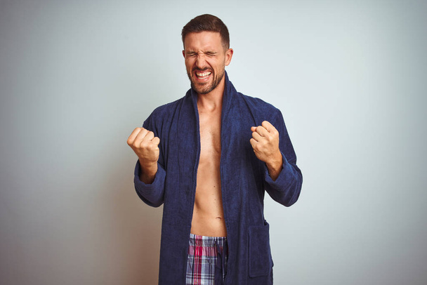 Σέξι shirtless άνθρωπος φορώντας άνετα πιτζάμες και ρόμπα πάνω από απομονωμένη φόντο πολύ χαρούμενος και ενθουσιασμένος κάνει χειρονομία νικητής με τα χέρια έθεσε, χαμογελώντας και ουρλιάζοντας για την επιτυχία. Έννοια εορτασμού. - Φωτογραφία, εικόνα