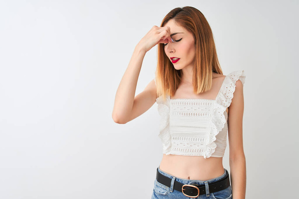 Krásná zrzaná žena, která nosí neformální tričko stojící nad izolovaným bílým pozadím, unavená mšením nosu a očí cítí únavu a bolest hlavy. Koncepce stresu a frustrace. - Fotografie, Obrázek