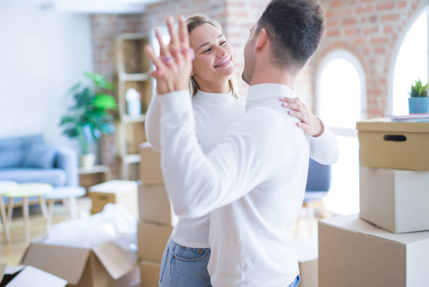 Joven hermosa pareja bailando en un nuevo hogar alrededor de cajas de cartón
 - Foto, imagen