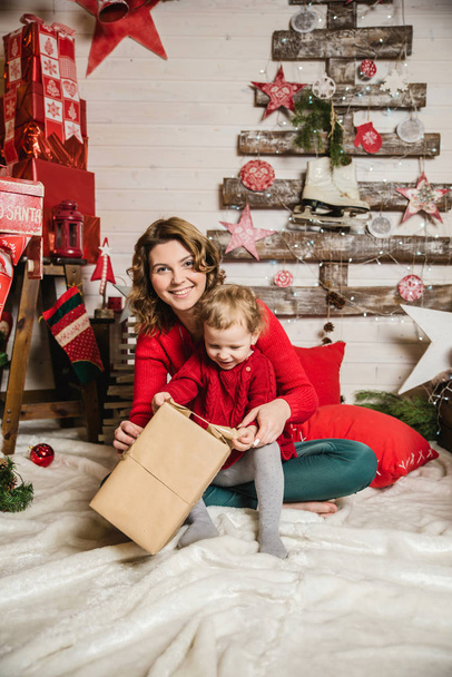 mother and daughter in red sweaters watching Christmas gifts - Fotografie, Obrázek