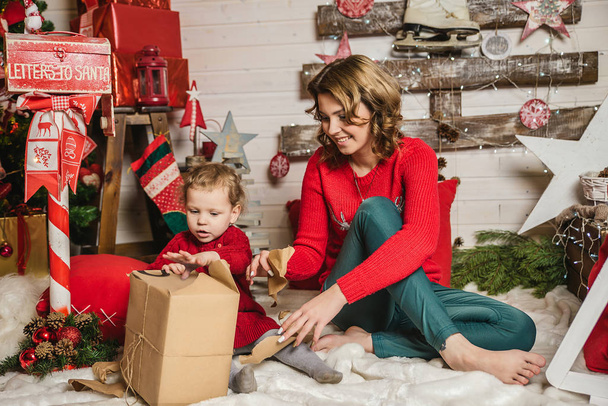 mother and daughter in red sweaters watching Christmas gifts - Foto, Imagen