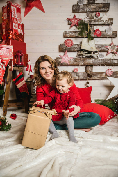 mother and daughter in red sweaters watching Christmas gifts - Photo, Image