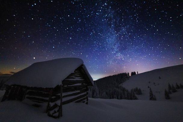 Fairytale landscapes of the winter Carpathian Mountains with a charming milky way in the sky tourist tents and snowy houses in the valleys - Fotoğraf, Görsel