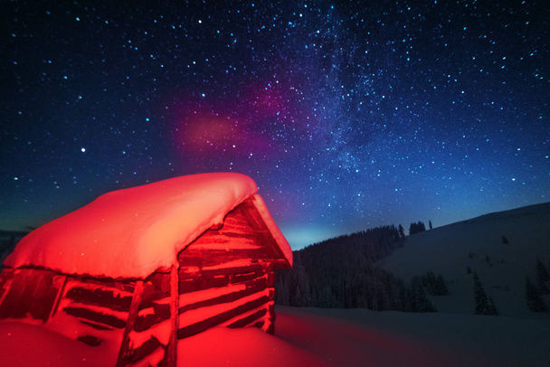 Fairytale landscapes of the winter Carpathian Mountains with a charming milky way in the sky tourist tents and snowy houses in the valleys - Photo, Image