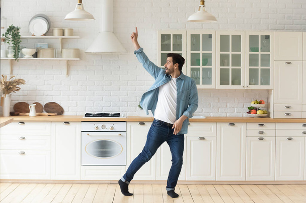Carefree funny young man having fun dancing alone in kitchen - Fotografie, Obrázek