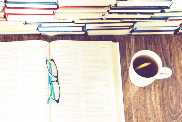 Stack of books education background, open book, glasses, and cup - Fotografie, Obrázek