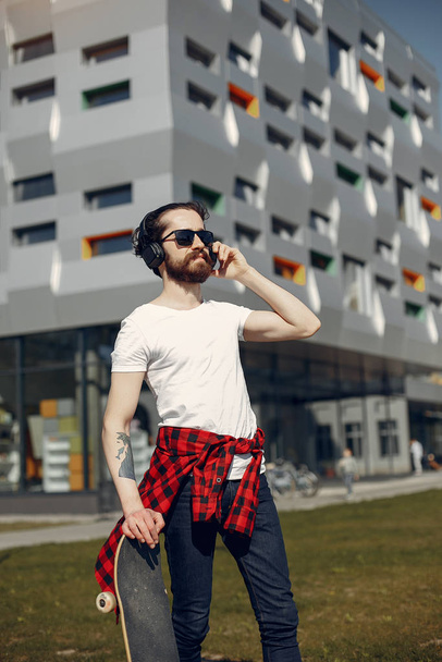 Stylish guy with skate in a summer city - Fotoğraf, Görsel